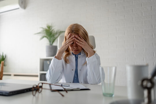 Female physician experiencing emotional exhaustion in a medical office. Mental health, workplace wellbeing, burnout prevention and healthcare professional support concept