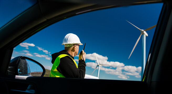 Engineer communicating at wind farm viewing through car window