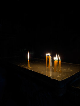 Burning candles in a church against a dark background, warm candlelight and spiritual atmosphere, traditional religious ritual