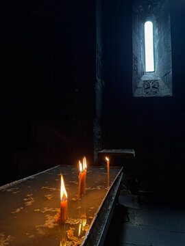 Burning candles in a church against a dark background, warm candlelight and spiritual atmosphere, traditional religious ritual