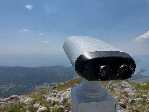 Binoculars overlooking the blue sea and majestic mountains, scenic Mediterranean landscape and travel sightseeing concept