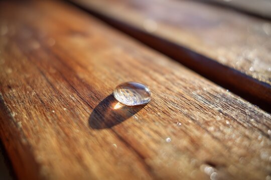 Macro shot of single drop of water on an outdoor teak deck sun drenched