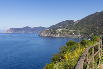 Fototapeta premium Coastal hiking trail within Cinque Terre in Italy with trail railing opening onto the coastal view, seen from eye-level trail viewpoint.
