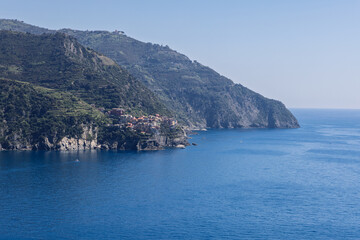 Fototapeta premium Manarola in the Liguria coastal region of northern Italy shows settlement dwarfed by steep coastal landscape in clear afternoon sun.