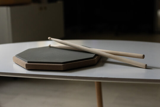 Drum practice pad and sticks resting on a table surface