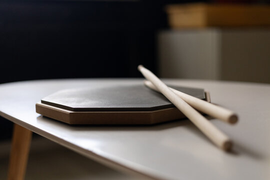 Drumsticks resting on a practice pad on a table
