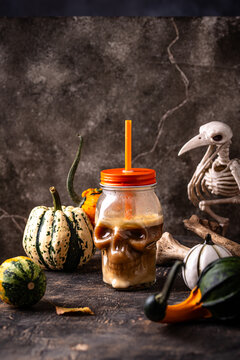 Halloween autumn drink pumpkin spicy latte in glass in shape of skull
