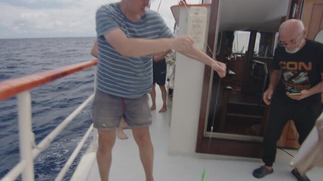Sailor catches fish from the sailing boat