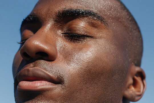 Close up portrait of smiling man with sweat on face after workout enjoying sunlight