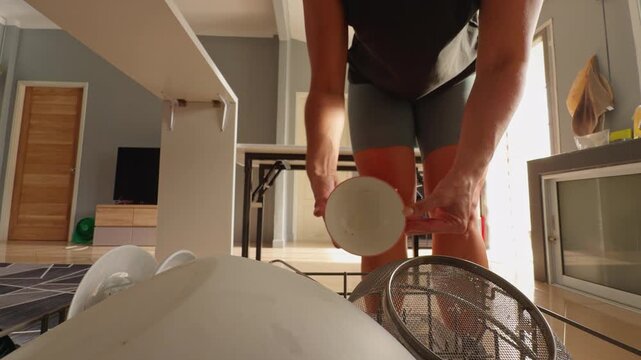 View from inside an Person Uses Bare Hands to Remove Clean Dishes From Dishwasher Rack in a Home Kitchen, Low Angle View Shows Household Cleaning and Daily Routine