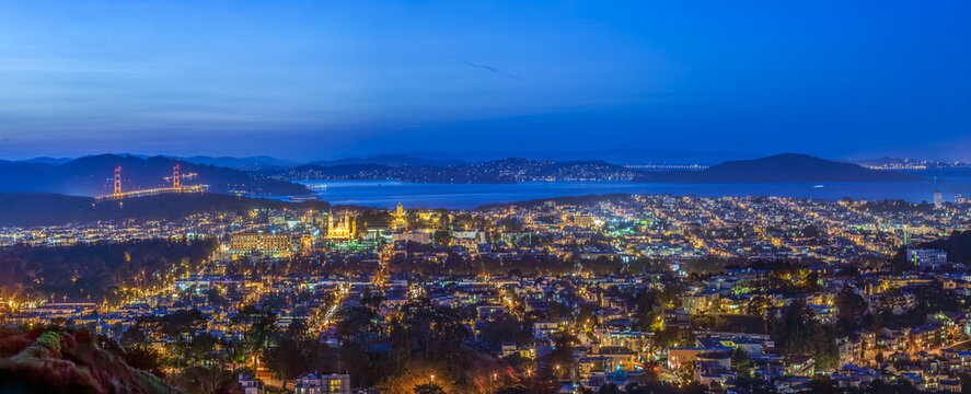 Wide panoramic view of San Francisco city lights and Golden Gate Bridge at night