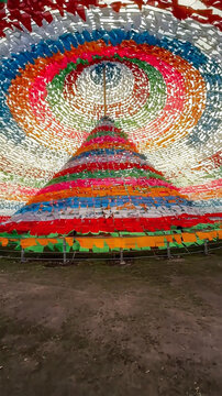 View of the Great Prayer Flag Area featuring a large conical structure covered in vibrant colorful prayer flags in Shangri-La, Yunnan, China.