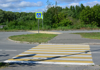 Pedestrian Crossing with Road Sign on Sunny Day with green trees in the background © Irina