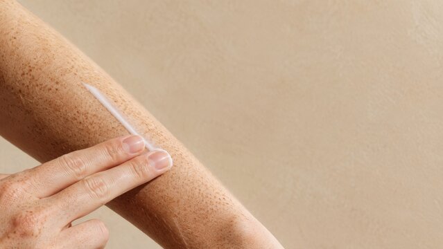Applying cream to freckled arm with copy space