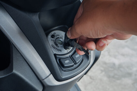 Motorcycle Ignition Switch Close Up with Hand Turning Key to Start Engine Scooter Security System