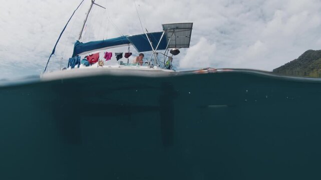 Splitted underwater view of the sailing boat with family with kids on it