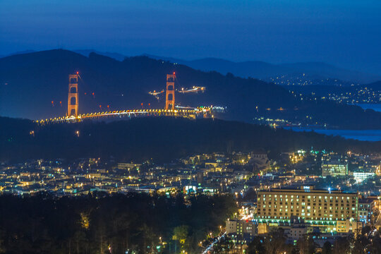 Illuminated Golden Gate Bridge and city skyline at night in San Francisco