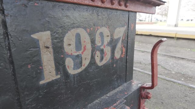 Close-up shot showing the year 1937 and metal rivets on the front of the steam locomotive exhibited in La Plata, Argentina. D-Log M, 10-bit color, flat log profile.