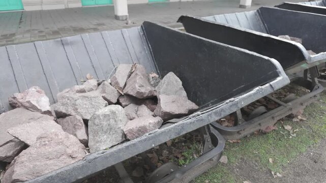 Close-up of metal tipping carts loaded with ballast stone at historic La Plata El Provincial station, Argentina. D-Log M, 10-bit color, flat log profile.