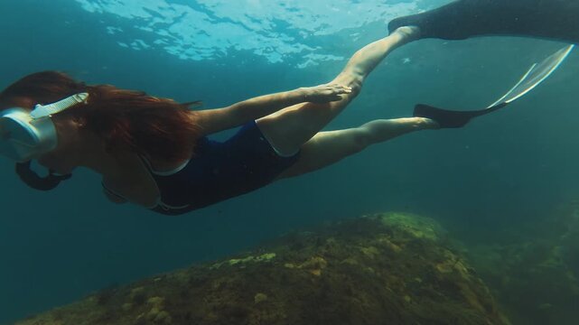 Young slim woman swims underwater, freediving and snorkeling in the sea near the coral reef near the island of Ilha Grande in Brazil