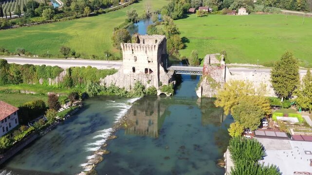 Aerial view of the medieval Visconti Bridge and ancient fortifications spanning the Mincio River in the village of Borghetto, Veneto, Italy.