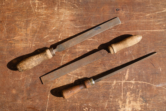 Three vintage hand file tools on rustic wooden workbench background