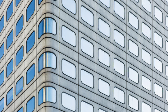 Geometric facade with repeating rounded windows and blue reflections in Hong Kong city, China. Abstract architecture background, symmetry, repetition, visual rhythm, minimalism, modern design