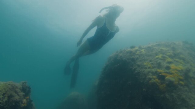 Young slim woman swims underwater, freediving and snorkeling in the sea near the coral reef near the island of Ilha Grande in Brazil