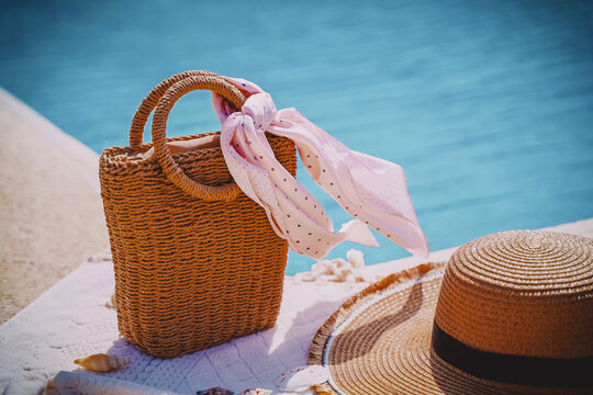 Woven beach bag and sun hat by the sea or pool