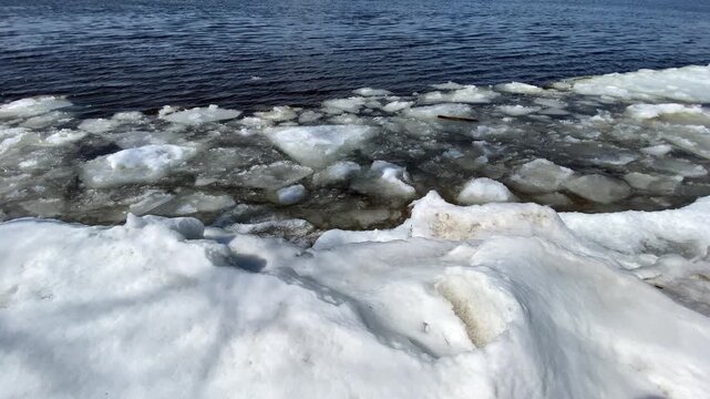 Water flowing from a concrete culvert storm drain pipe into a rocky creek bed during winter snowmelt in a forest.