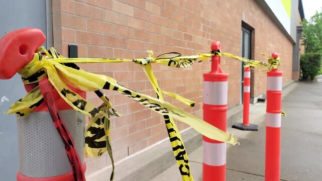 Orange traffic delineator posts with yellow caution tape blocking sidewalk path