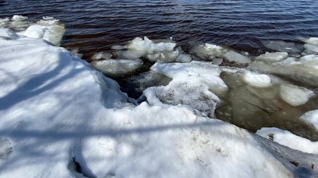 Water flowing from a concrete culvert storm drain pipe into a rocky creek bed during winter snowmelt in a forest.