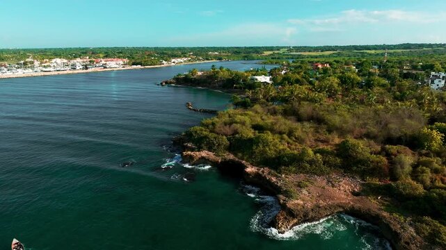 Aerial view of Boca Chavon river mouth with lush tropical vegetation and rocky coastline along the Caribbean Sea in La Romana, La Romana, Dominican Republic.