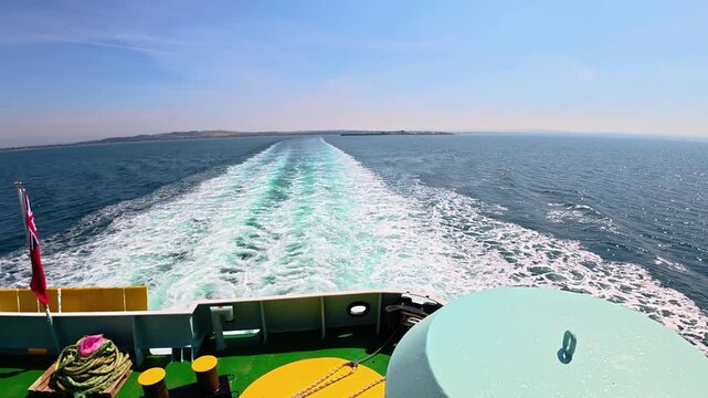 Ferry boat generating white foam wake on a blue ocean under a clear sky