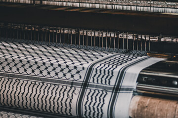 Fototapeta premium Traditional keffiyeh fabric moving through a weaving machine