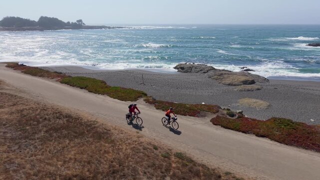 A man and woman bike along the coastal trail in Fort Bragg California near Mendocino while taking in the Pacific Ocean views.
