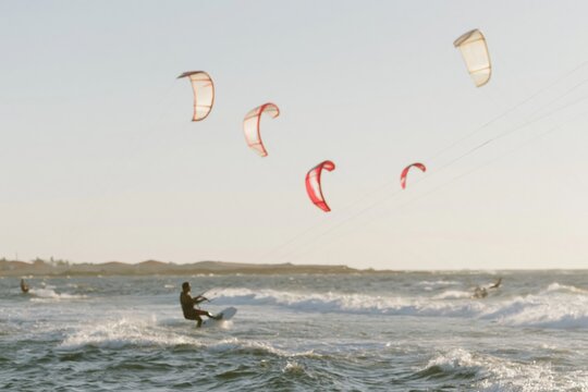 Silhouette of a kite surfer riding a wave on a bright afternoon for extreme sports and coastal lifestyle branding