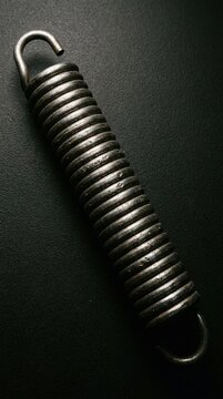 Metal spring rests on dark textured surface