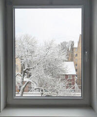 Fototapeta premium Winter city view from the window with snowy trees and buildings
