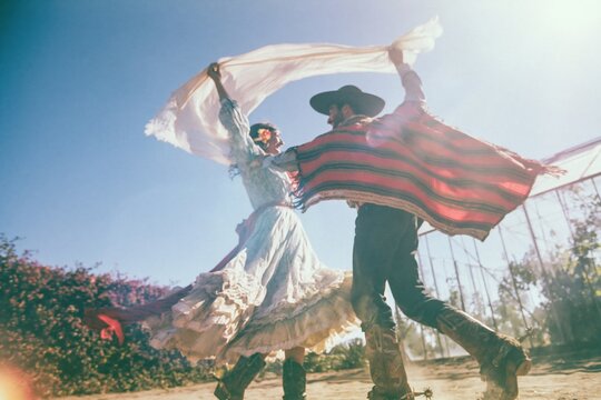 Huaso couple dancing the cueca in traditional attire on a sunlit dirt ground for Chilean heritage and cultural tourism promotion