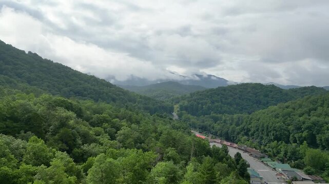 Aerial view near Cherokee, North Carolina, showing roads and buildings surrounded by lush forested mountains, low clouds, and drifting mist.