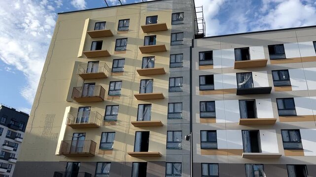 Painting the facade of residential building. New facade block building before painting. Building Construction, renovation. Construction work at height, facade cleaning, plastering. Insulation and wall