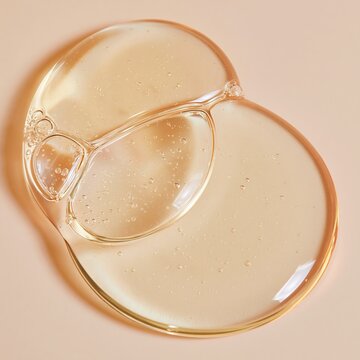 Macro close-up of three-way split serum drops on a smooth surface, showcasing transparent gel-like texture with bubbles and reflections