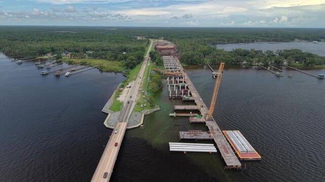 Aerial view of Shands Bridge construction showing heavy machinery and concrete pillars over the St. Johns River, St. Augustine, Florida, United States.