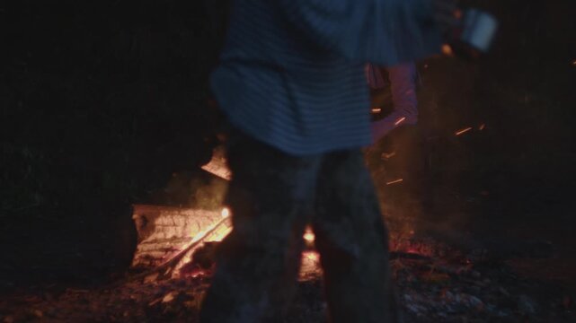 Young woman sits in front of the bonfire burning in the wild