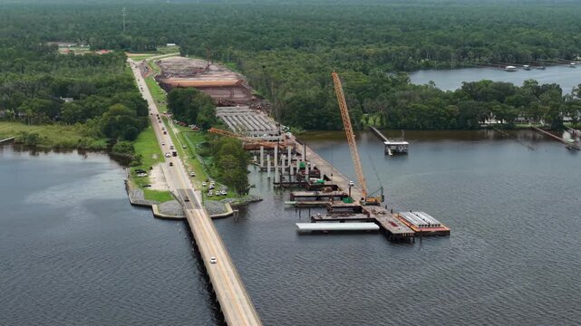 Aerial view of the Shands Bridge construction project featuring a large crane and bridge piers over the St. Johns River in St. Augustine, Florida, United States.