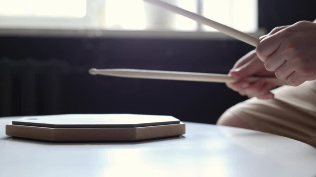 Close-up of hands practicing drum beats on a practice pad with sticks