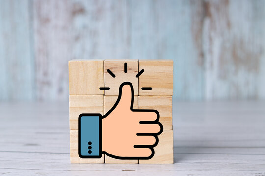 Thumbs-up symbol on a wooden block representing approval, positive feedback, and success; icon on wooden cubes. Realistic.