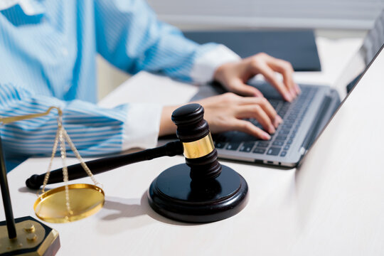 Legal technology concept. Professional using laptop beside gavel and justice scale represents digital law, compliance, legal research, court work, regulation