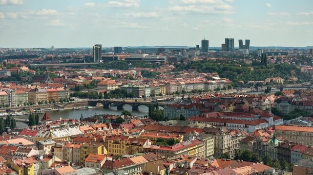 Panoramic cityscape of historic Prague features Vltava River bridges and urban architecture. Modern business district towers rise on the horizon under sunny blue sky. European capital travel.